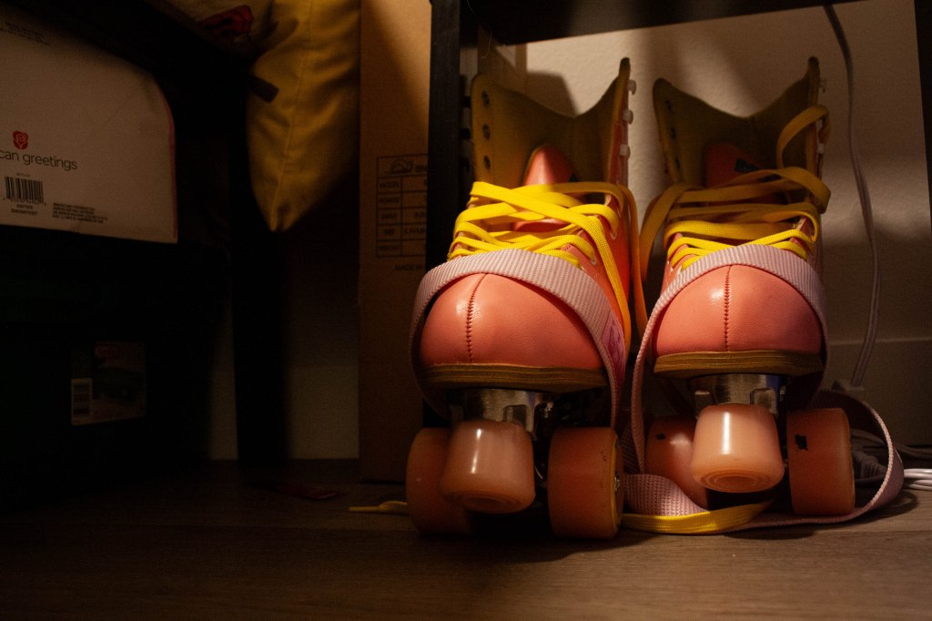 A low-ground image of pink roller skates with yellow laces