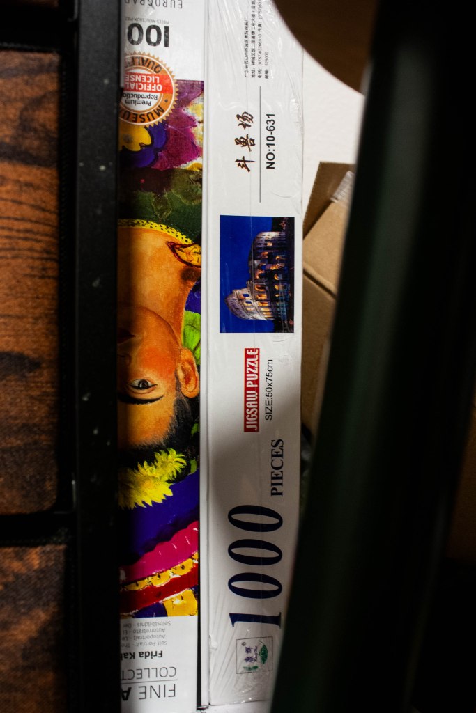 A close-up image of two puzzles, one with an image of Frida Kahlo peeking between the foreground
